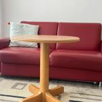 Rotes Sofa mit Kissen und runden Tisch auf Teppich