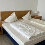 Zwei Einzelbetten mit weißen Bettwäsche und Nachttischen mit Lampen.