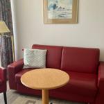 Ein Wohnzimmer mit rotem Sofa, runder Tisch und Stehlampe.