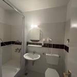 Badezimmer mit Dusche, Waschbecken und Toilette.