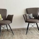 Zwei braune Sessel mit Kissen und Plüschtieren stehen auf Holzboden.