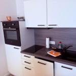 Küche mit Dunstabzug, Spüle, Herd und Backofen.