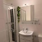 Badezimmer mit Dusche, Waschbecken und Toilette. Pflanze an der Wand.