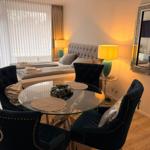 Ein Schlafzimmer mit einem Bett, einem runden Tisch und vier Stühlen. An der Wand hängt ein Spiegel.