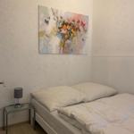 Ein Schlafzimmer mit weißem Bett, Nachttisch und Wandbild mit Schmetterlingen.