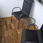 Terrasse mit zwei schwarzen Stühlen und einem runden Tisch auf Holzboden