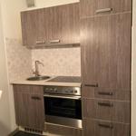 Küche mit Holzfronten, Spüle, Kochfeld und Ofen. Fliesenwand mit Muster.