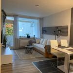 Wohn- und Essbereich mit Sofa, Tisch und Stühlen. Fenster mit Blick auf Balkon.