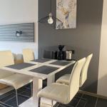 Essbereich mit weißem Tisch, weißen Stühlen und Dekorationsbild an der Wand.