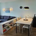 Wohn- und Essbereich mit Sofa, Esstisch und Küchenzeile. Blick auf grüne Landschaft.