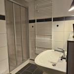 Badezimmer mit Dusche, Waschbecken und Heizkörper.
