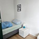 Ein Schlafzimmer mit einem Bett, Nachttisch und Teppich auf Holzboden.