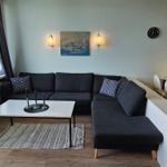 Wohn- und Essbereich mit Sofa, Tisch und Blick auf die Berge.