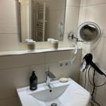 Waschbecken mit Spiegel, Handtuch und Haartrockner an der Wand.