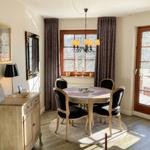 Esszimmer mit runder Tisch, vier Stühlen und Fensterblick auf Schnee.