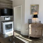 Wohnzimmer mit Fernseher, Kamin und Holzmöbel. Wandbild und Lampe sind sichtbar.