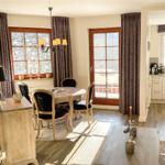 Esszimmer mit Tisch, Stühlen und Blick auf Balkon.