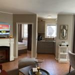 Wohnbereich mit Küche, Fernseher und Kamin. Blick in Schlafzimmer.