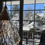 Durch die Glastür blickt man auf eine verschneite Terrasse mit Gartenmöbeln und schneebedeckten Bäumen.