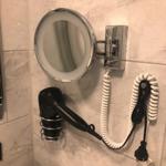 Wandmontierte Haartrockner- und Spiegelanlage mit Lichtumrandung und Steckeranschluss.