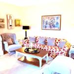 Wohnzimmer mit Sofa, Sessel und Couchtisch. Wanddekoration und Beleuchtung.