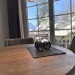 Runder Holztisch mit Stühlen und Fensterblick auf verschneite Bäume.