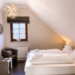 Schlafzimmer mit Dachschrägen, Bett, Fenster und Sitzgelegenheit.