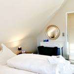 Schlafzimmer mit Dachschräge, Bett, Schreibtisch und Spiegel.