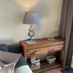 Holzsideboard mit Lampe und Hirschfigur neben Fenster mit Vorhängen