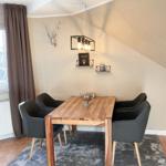 Esszimmer mit Holztisch, vier Stühlen und Deckenleuchte. Wanddekoration mit Hirschgeweih.