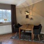 Esszimmer mit Holztisch, vier Stühlen und Fensterblick auf verschneite Landschaft.