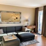 Ein Wohnzimmer mit grauem Sofa, Spiegel und Terrassentür.