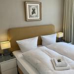 Schlafzimmer mit Doppelbett, Nachttischen und Bild an der Wand.