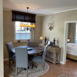 Esszimmer mit runden Tisch, grauen Stühlen und Deckenventilator. An der Wand hängt ein Hirschgeweih.