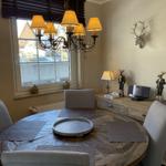 Rundes Esszimmer mit Holztisch, Stühlen und Deckenleuchte. Wanddekoration mit Hirschgeweih.