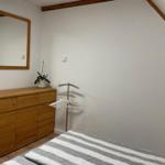 Schlafzimmer mit Bett, Kleiderschrank und Spiegel an der Wand.