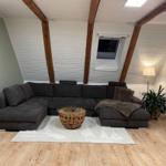 Wohnzimmer mit Ecksofa, Holzboden und Dachfenster.