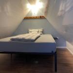Schlafzimmer mit Dachschräge, Bett und Holzboden.