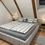 Schlafzimmer mit Doppelbett, Holzboden und schrägen Dachbalken.