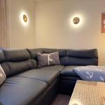 Ein Ecksofa mit Kissen und einer Decke mit Ankern liegt vor einem Tisch.