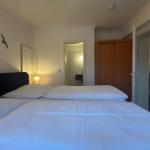 Schlafzimmer mit Doppelbett, Wanddekoration und Blick in Bad und Küche.