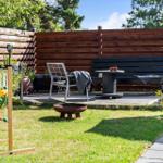 Backyard with wooden deck, seating, and lawn game on grass.