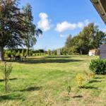 Large garden with seating areas and trees under a blue sky.