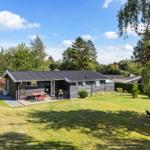 A house with terrace, garden, and seating areas under trees.