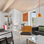 Living and dining area with sofa, table and chairs under wooden ceiling.