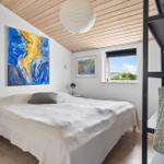 Bedroom with bed, wall art, and window with view of greenery.