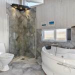 Bath with shower, bathtub, and toilet. Wooden walls and window with view.