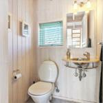 Bathroom with toilet, sink, and window with blinds.