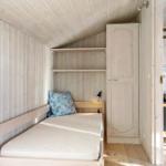 A bedroom with a bed, a shelf unit, and a wardrobe.