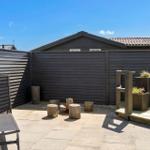 Terrace with sun lounger, wooden stools, and planters. Background: wooden fence and roof.